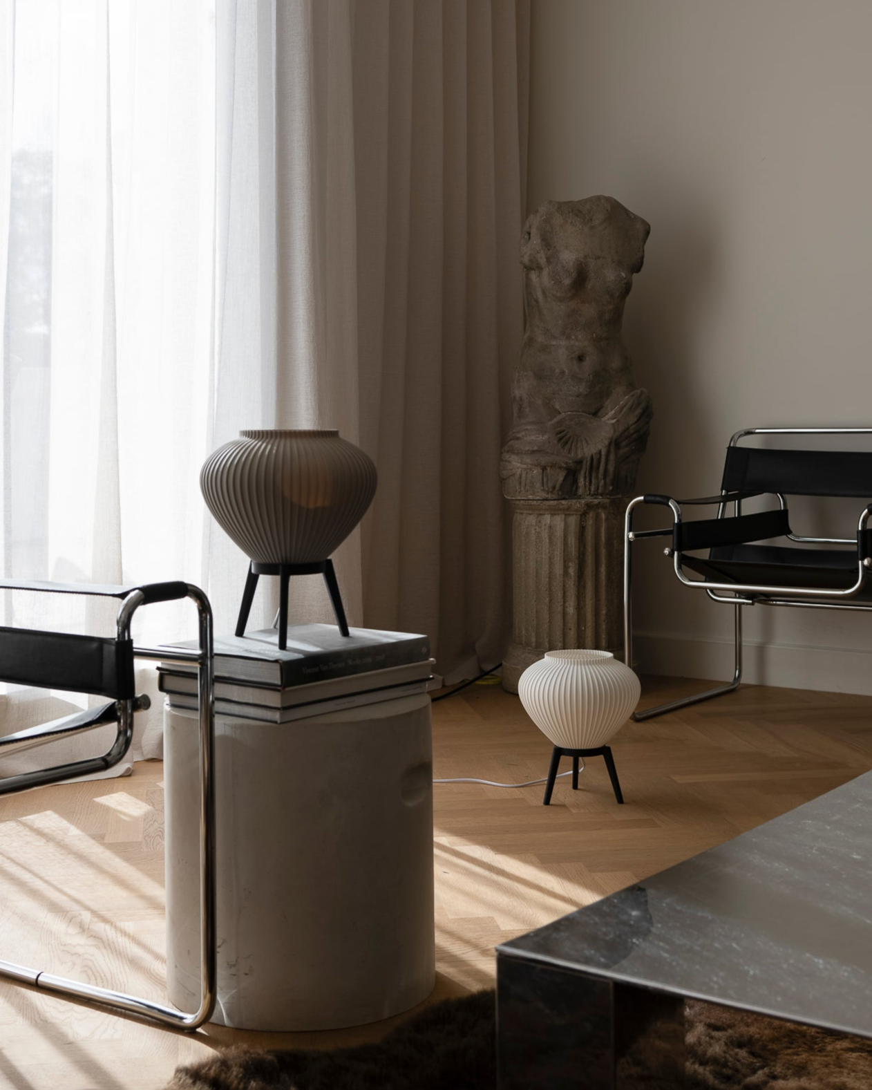 Modern interior with black chairs, a sculpture, and a vase near a window.