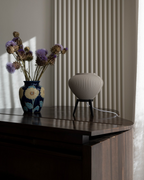 Decorative vase with flowers on a piano next to a radiator.