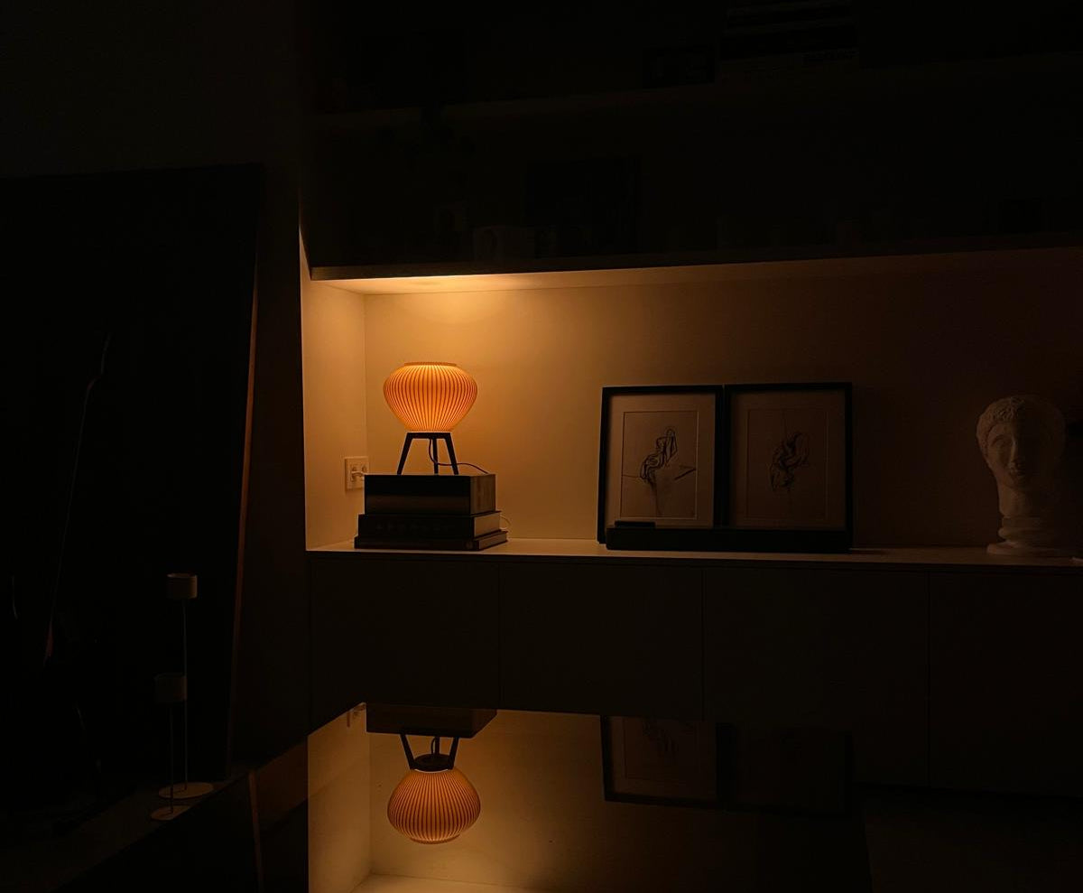 Dimly lit room with a small table lamp on a shelf.
